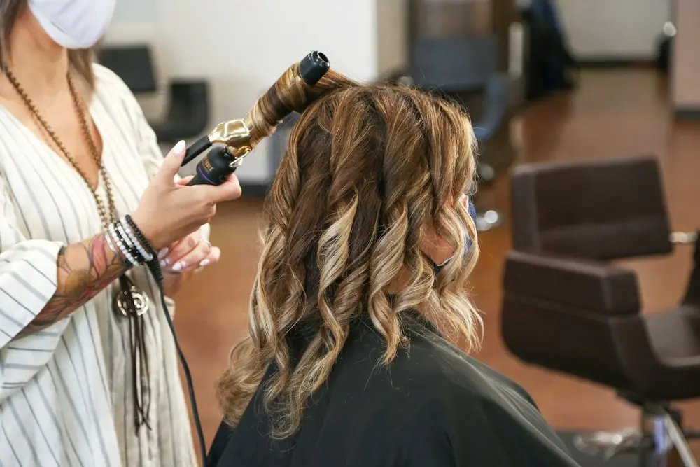 Peluquera rizando el cabello con tenacilla: alisado orgánico en Zaragoza